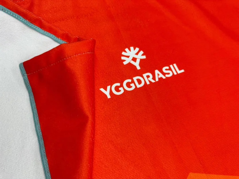Red towel with embroidered Yggdrasil logo, showcasing embroidery service.