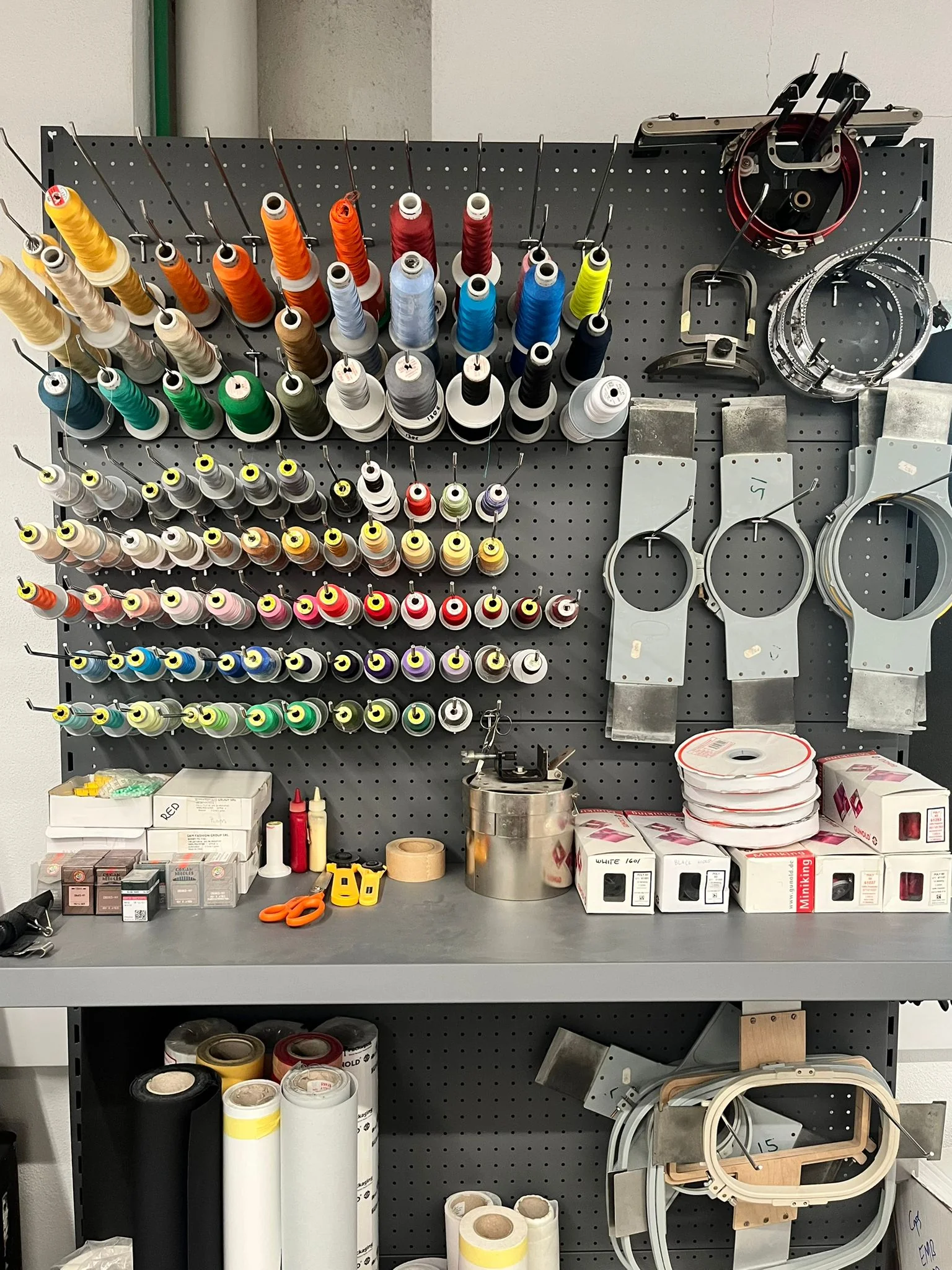 Embroidery machine with colourful threads in a workshop setting.