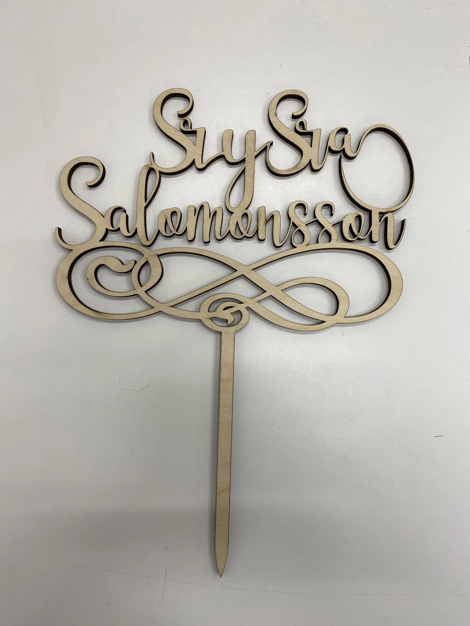 Laser-cut wooden cake topper with script text.