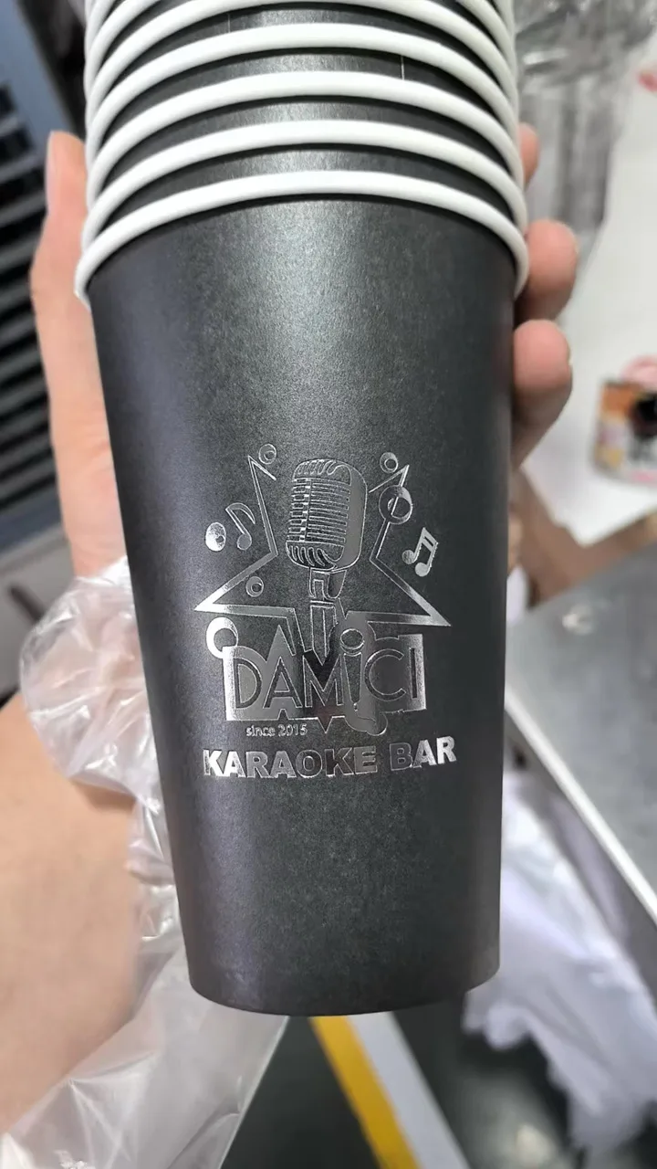 Stack of black paper cups with silver foil D'Amici Karaoke Bar logo.