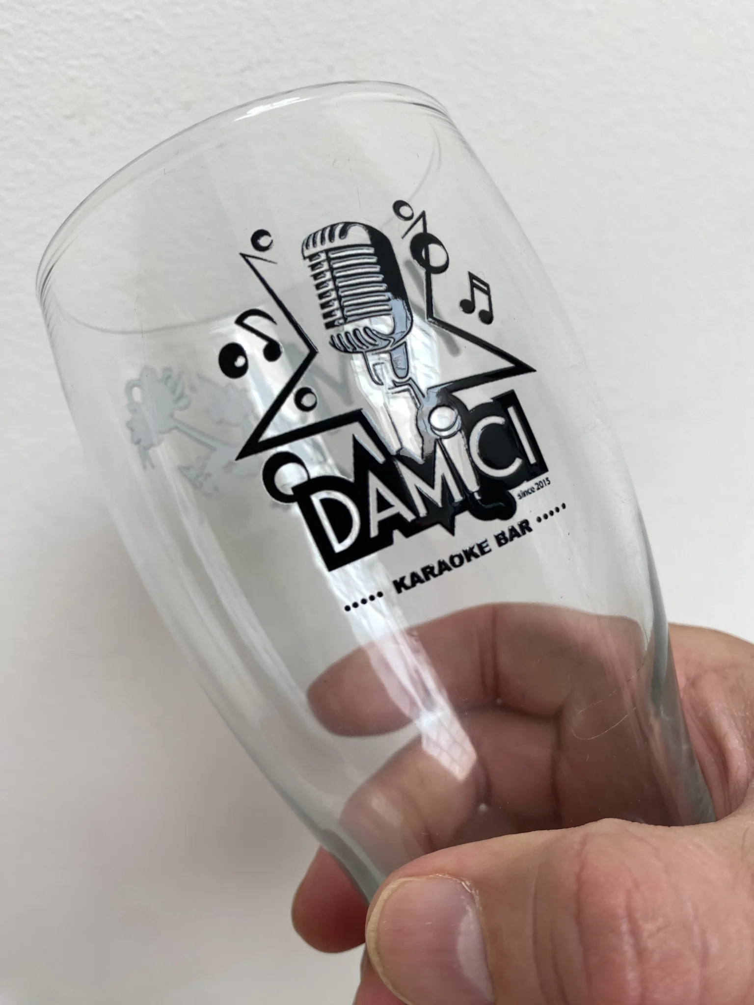 Printed pint glass with karaoke bar logo and musical design.