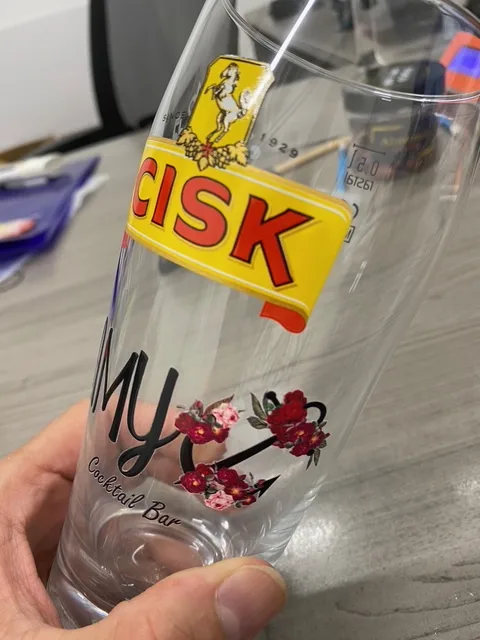 Cisk pint glass printed with AMY Cocktail Bar floral logo, custom glass printing.